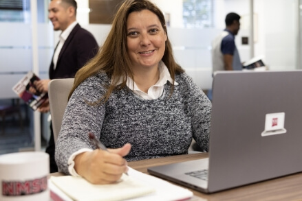 A NMSU student sitting at a table using a laptop computer