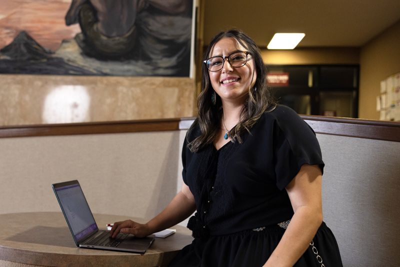 A smiling woman poses with a laptop computer.