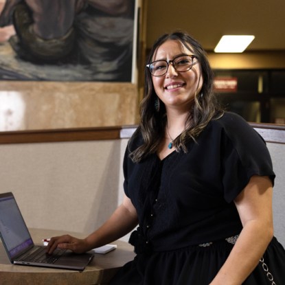 A smiling woman poses with a laptop computer.