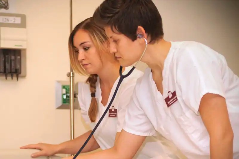 Two Master of Science in Nursing students in uniform practice a patient examination — NMSU Global Campus