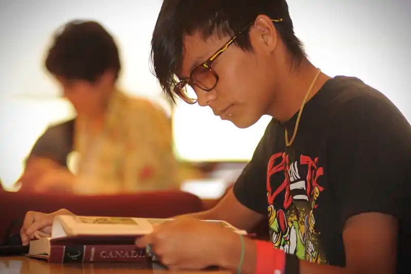 A young woman reading a textbook — NMSU Global Campus