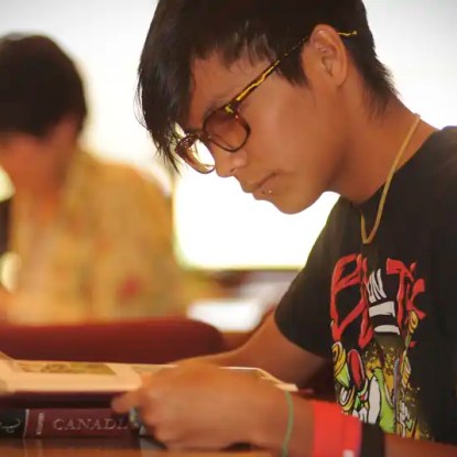 A young woman reading a textbook — NMSU Global Campus