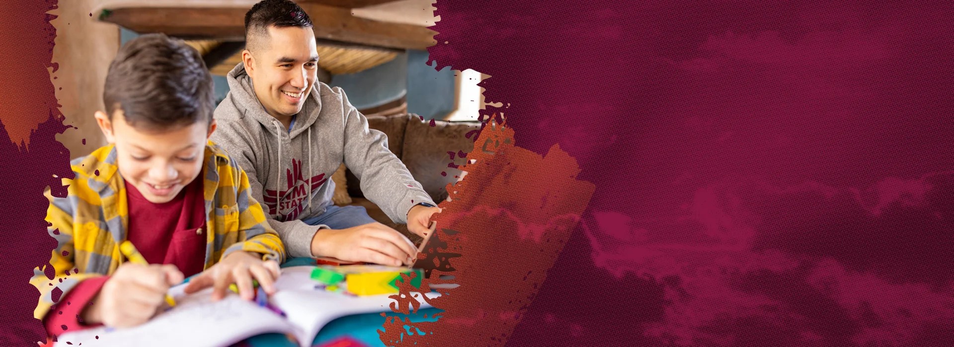 An adult learner studies on a laptop while his son sits beside him with a coloring book.