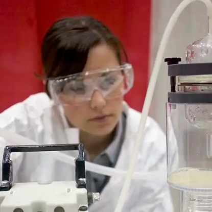 A lab technician in PPE gear working on an experiment — NMSU Global Campus