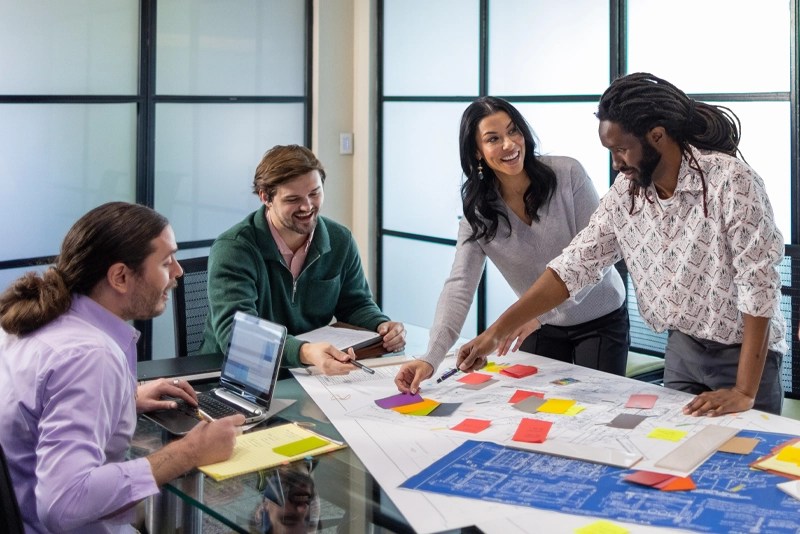 Four cheerful coworkers collaborate in a conference room