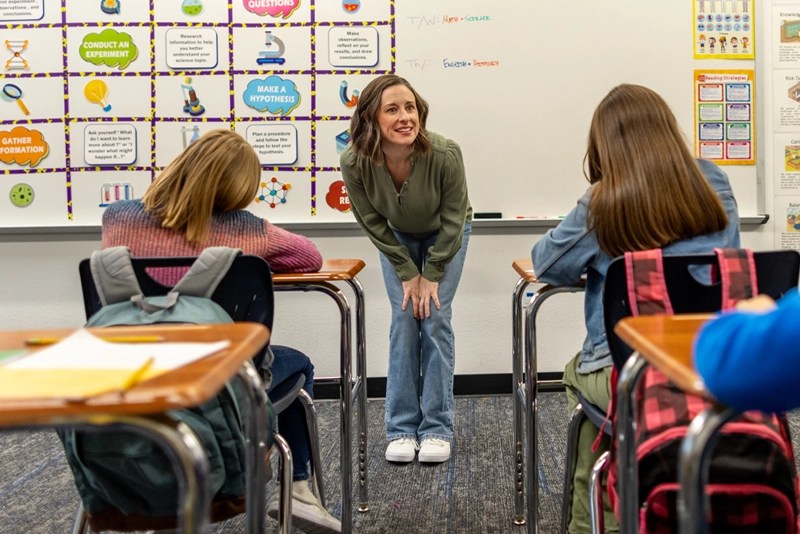 a smiling teacher faces her young students in an elementary school classroom