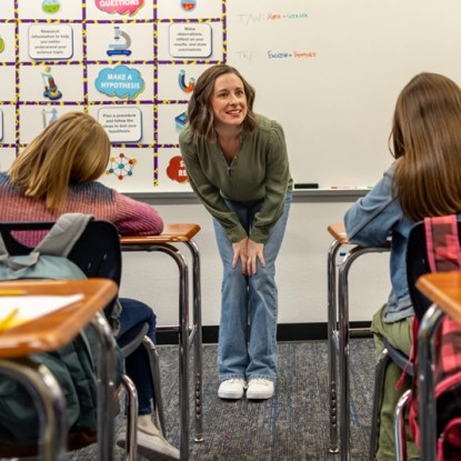 a smiling teacher faces her young students in an elementary school classroom