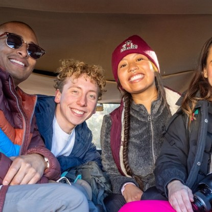 a smiling group of college students sitting in a car