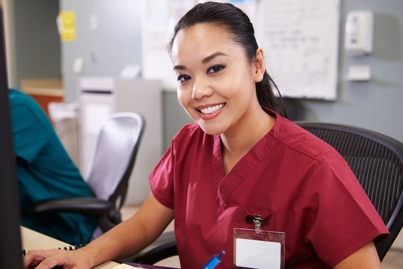 A smiling woman wearing medical scrubs