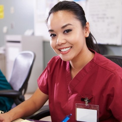 A smiling woman wearing medical scrubs