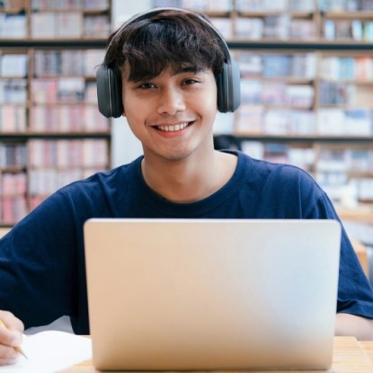 a boy wearing headphones and sitting at a desk with a laptop