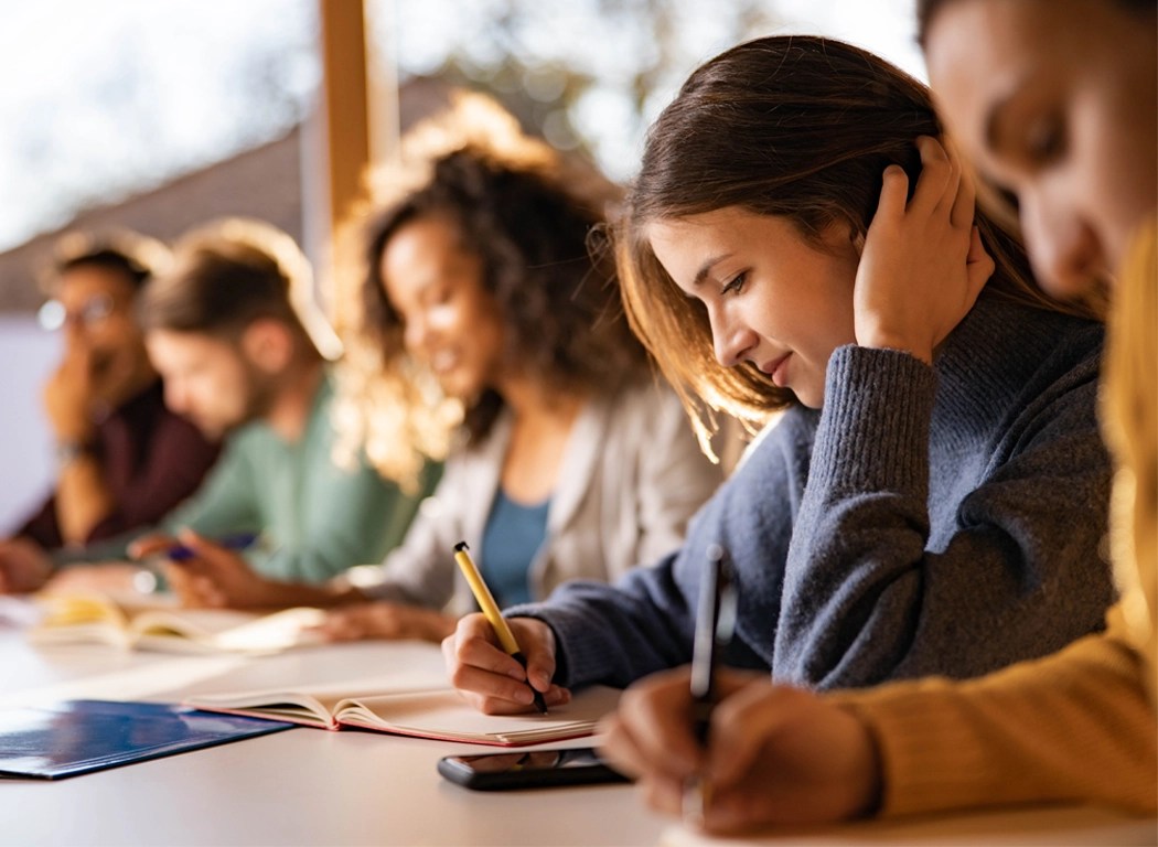 a group of adult students writing at their desks in a classroom