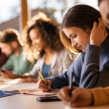 a group of adult students writing at their desks in a classroom