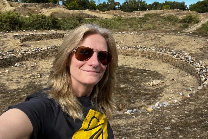 A woman wearing sunglasses takes a selfie in the desert