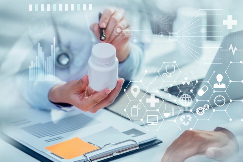 close-up of hands holding a bottle of medicine beside a clipboard and a laptop computer