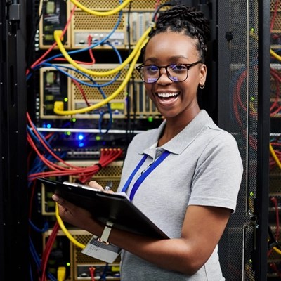 A technician takes notes on her clipboard in a computer room