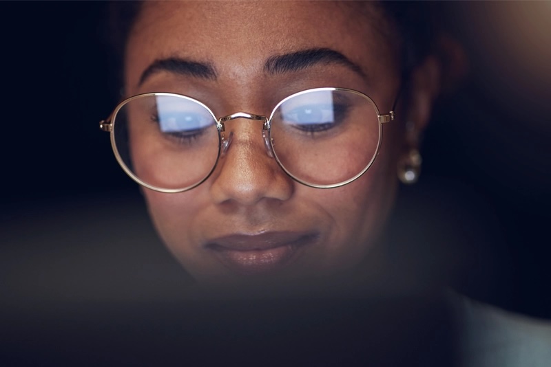 A computer screen reflects in a woman's eyeglasses as she looks up 8-week online courses at NMSU Global Campus.
