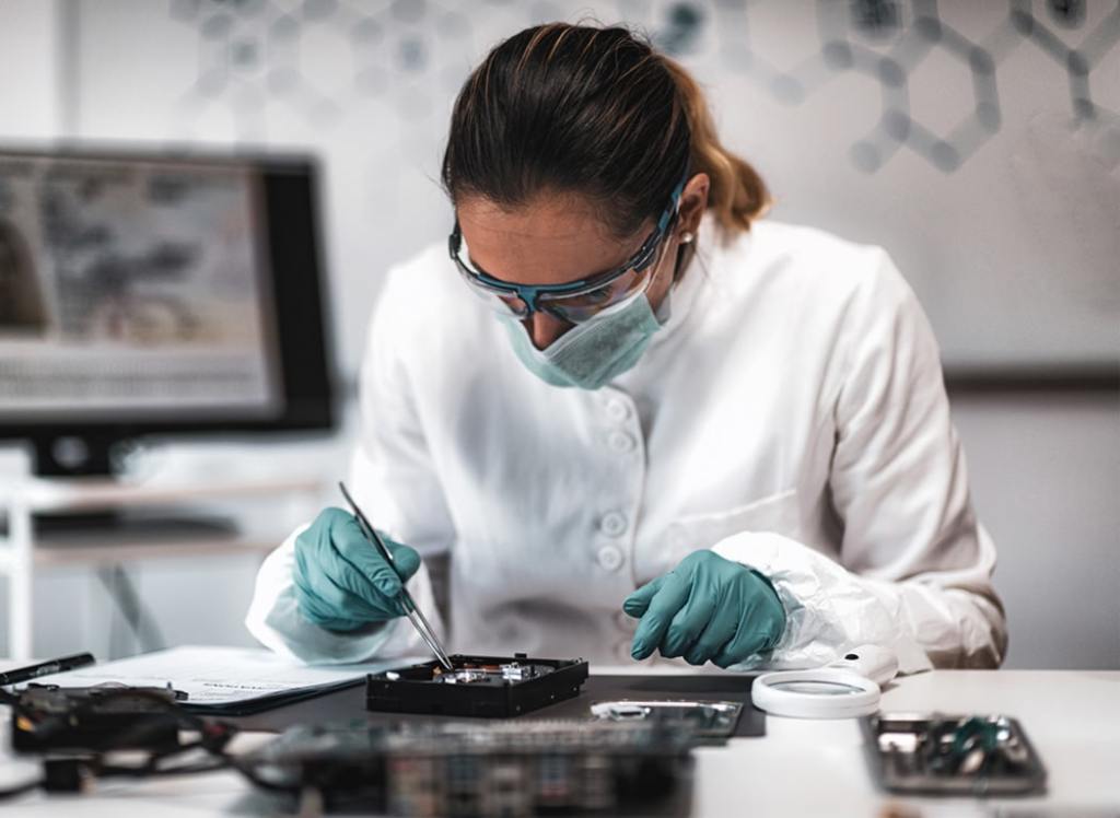 Scientist wearing protective gear working on electronics in a lab