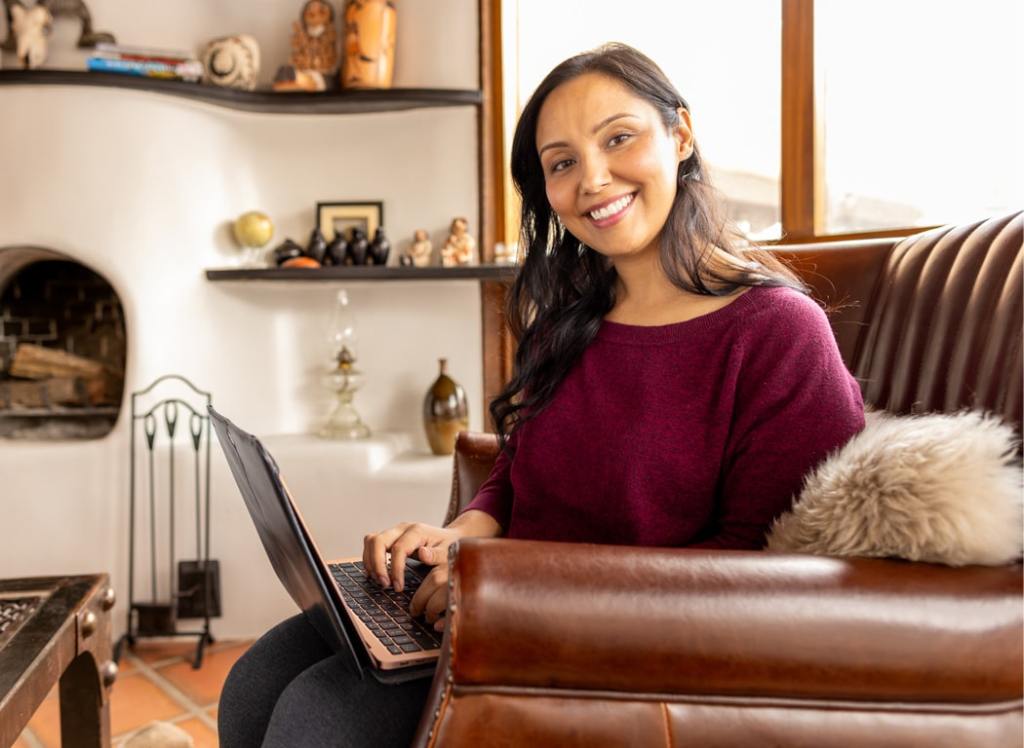 Smiling student sitting at a desk with a laptop and papers