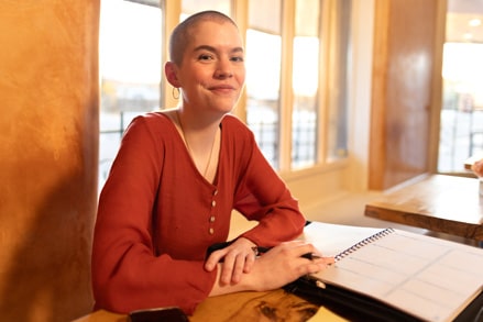 Person with a red blouse sitting at a table with a planner