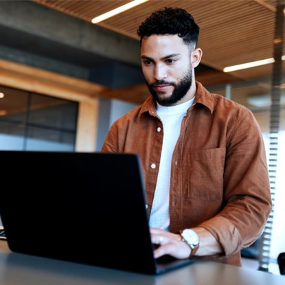 Adult learner using a laptop to complete a flexible microlearning course online in a modern office setting