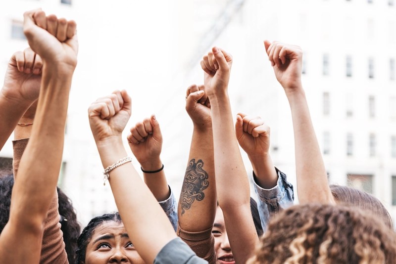 Group of diverse people raising fists in solidarity at a social justice event