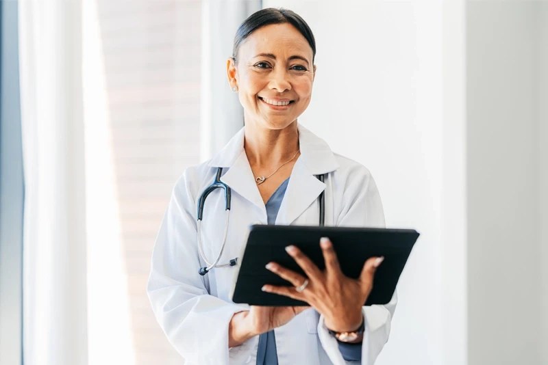 Doctor smiling while looking at a digital tablet