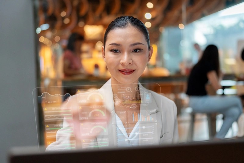 A professional woman analyzes data dashboards on a transparent screen using skills gained in an online master’s degree program in data analytics.