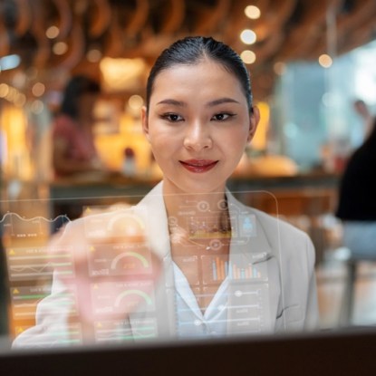A professional woman analyzes data dashboards on a transparent screen using skills gained in an online master’s degree program in data analytics.