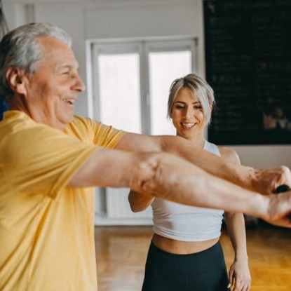 Trainer guiding older adult with resistance bands — study kinesiology and pre-PT at NMSU Global Campus