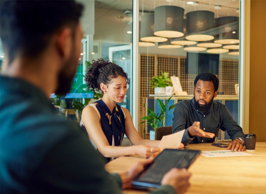 A group of young professionals sit around a conference table using business fundamentals from a NMSU Global Campus microlearning course