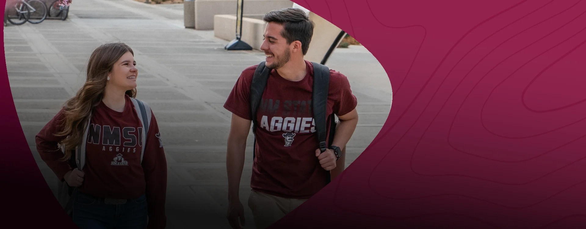 Two college students in NMSU Aggies T-shirts walking and smiling — New Mexico State University Global Campus