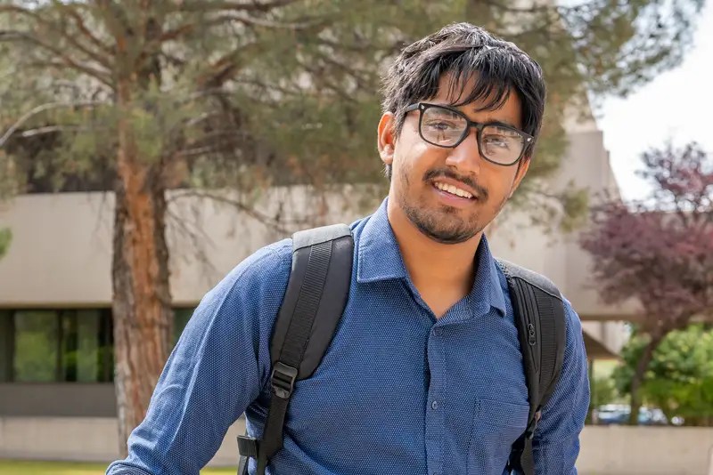 A male college student wearing glasses and a backpack — New Mexico State University Global Campus