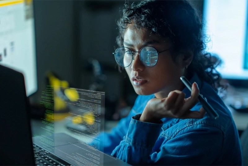 Engineer reviewing machine learning code with digital data overlays — New Mexico State University Global Campus