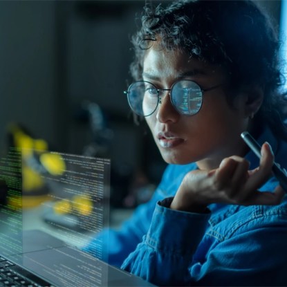 Engineer reviewing machine learning code with digital data overlays — New Mexico State University Global Campus