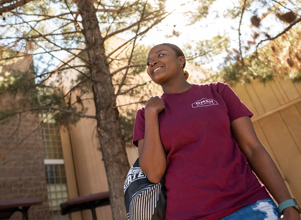 A woman in a crimson NMSU Aggies t-shirt — New Mexico State University Global Campus