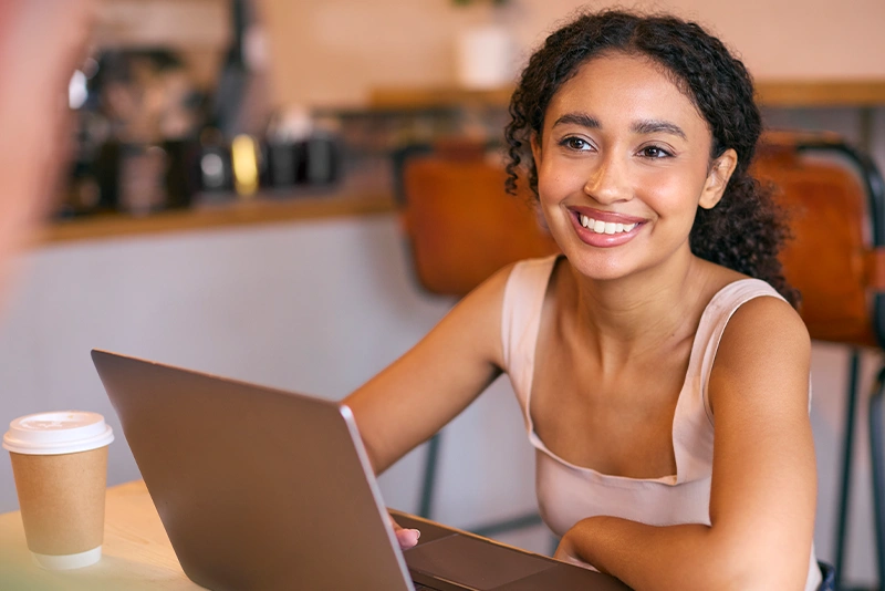 A New Mexico State University Global Campus online college student smiles at her laptop computer