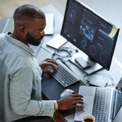 A data analyst using computers at his workstation