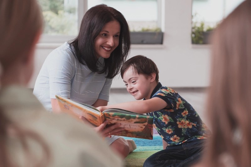 A special education teacher reads a book with a child