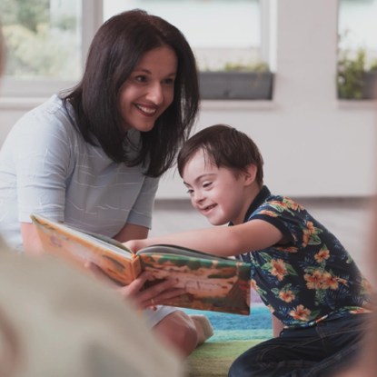 A special education teacher reads a book with a child