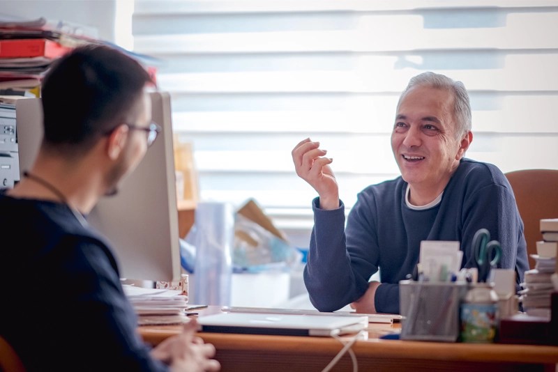 A higher education administrator talking with a college student in an office