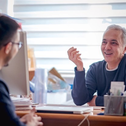 A higher education administrator talking with a college student in an office