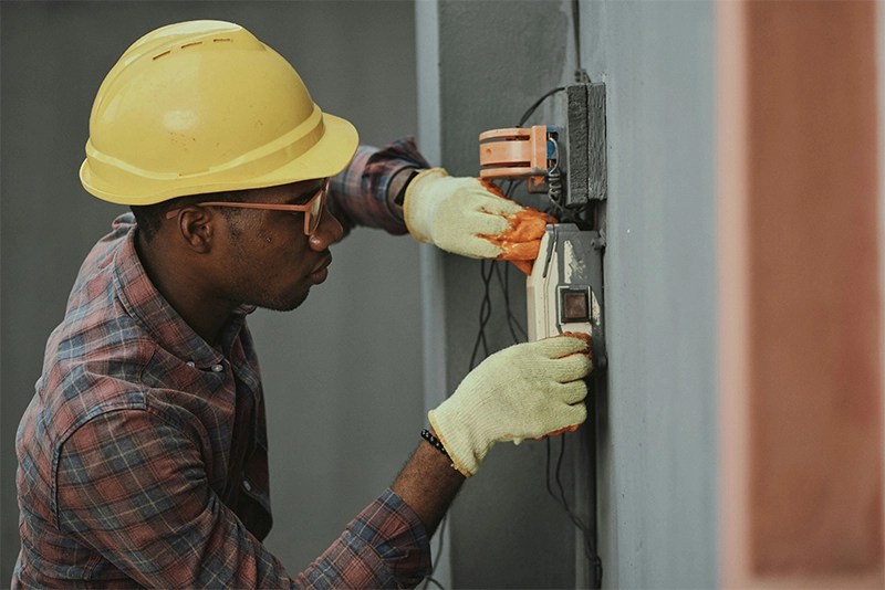 An engineer in a hardhat working on an electrical panel