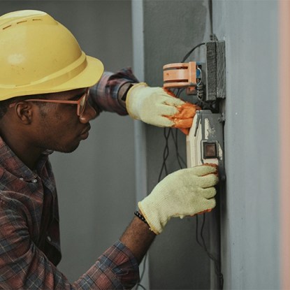 An engineer in a hardhat working on an electrical panel