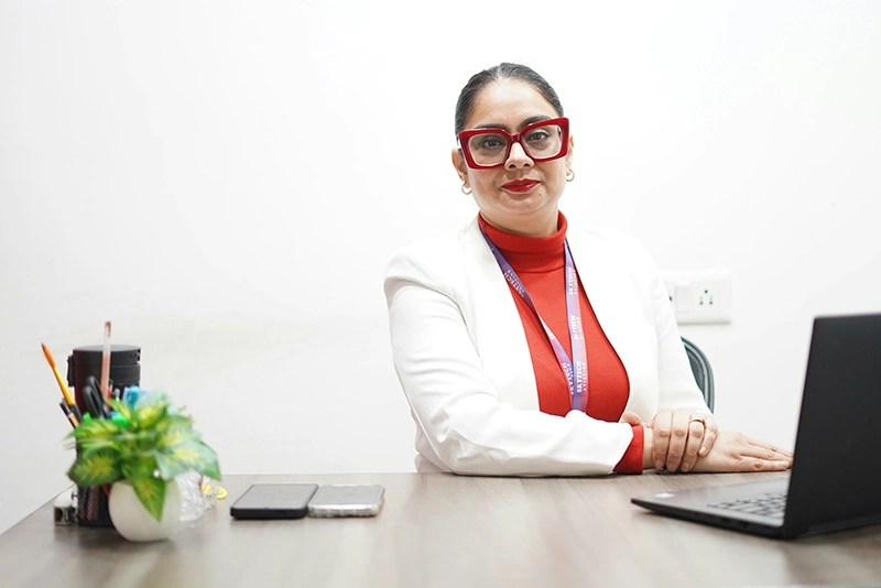 A woman posing while seated at a desk