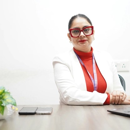 A woman posing while seated at a desk
