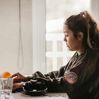 A woman in a military jacket typing on a laptop computer keyboard