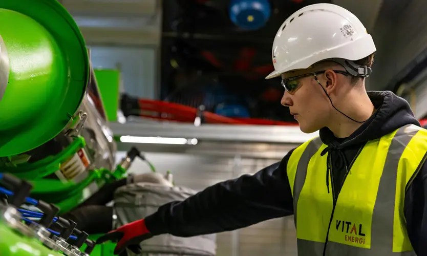 Chemical engineer inspecting industrial processing equipment in a safety helmet and high-visibility vest