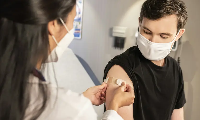 A nurse putting a bandage on a patient's upper arm