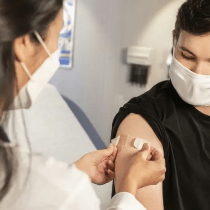 A nurse putting a bandage on a patient's upper arm